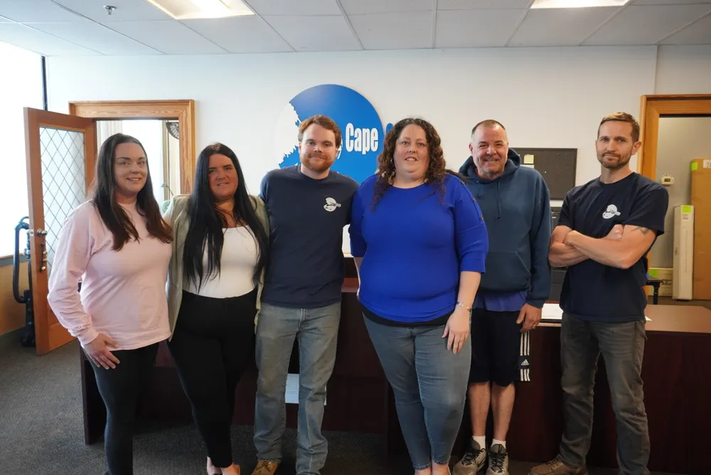 Six members of the Cape Cargo team standing in front of the company logo